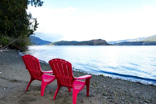 科威恰湾Sea and Cedar Retreat-a home in a tranquil setting的两把红色椅子坐在靠近水面的海滩上