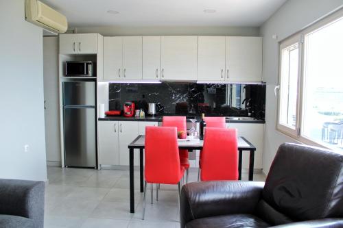 海若克利欧MAXIM APARTMENT的厨房配有餐桌和红色椅子