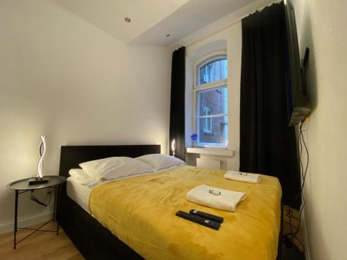 托伦Central Rooms Apartment的一间卧室配有一张带黄色毯子和窗户的床