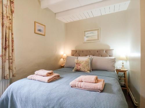 罗宾胡兹贝Delft Cottage的一间卧室配有带粉红色毛巾的床