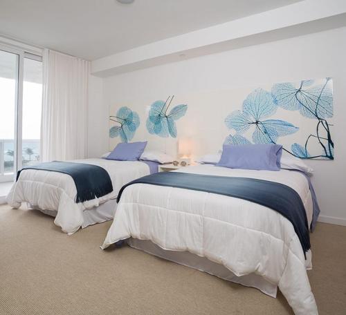 哈兰代尔海滩Stunning 2 Bedroom Bay Front Apt w/ Breathless View 1909的卧室内的两张床,墙上挂着蓝色蝴蝶
