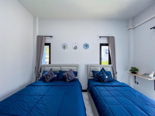 素叻286poolvilla的白色客房 - 带2张蓝色的床和窗户