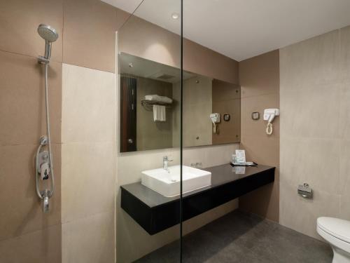 棉兰d'primahotel Kualanamu Medan Formerly Prime Plaza Hotel的一间带水槽和玻璃淋浴的浴室
