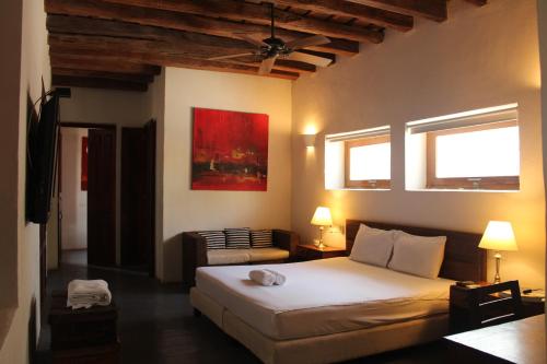 圣玛尔塔Casa Gaitana - Alma Hotels的一间卧室配有一张床和一把椅子,还有两个窗户