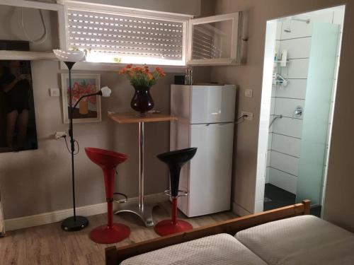 特拉维夫Bialik St B&B room Bauhaus district Tel Aviv的客厅配有冰箱和2张红色凳子