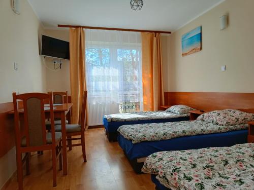 科沃布热格Pensjonat Przystań的酒店客房设有三张床、一张桌子和一张书桌。