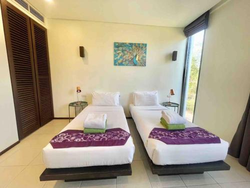 Ban Lum FuangBang Tao Garden Beach - Penthouse的紫色床单的客房内的两张床