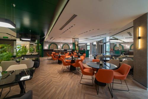 阿克套Dostyk Business Hotel的自助餐厅里设有橙色椅子和桌子的餐厅
