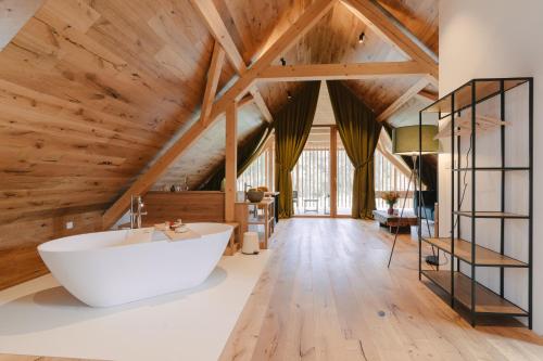 波斯托伊纳PIRA HOTEL的浴室配有大型白色浴缸和木制天花板