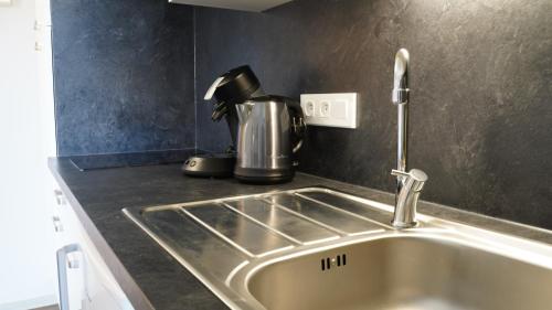 里摩日Apparts Confort 87的厨房柜台设有水槽和咖啡壶