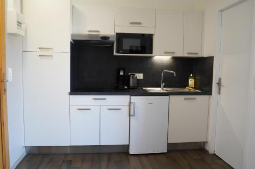 里摩日Apparts Confort 87的白色的厨房配有白色橱柜和水槽