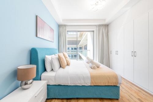 拉斯阿尔卡麦Luxury 1BR Beachfront Apartment Marjan Island的蓝色的卧室设有床和窗户