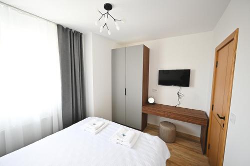 兹拉蒂博尔Tasa Apartmani的一间卧室配有一张床,墙上配有电视