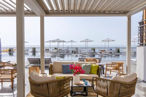 贾迪尼-纳克索斯Delta Hotels by Marriott Giardini Naxos的天井配有沙发、桌椅