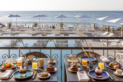 贾迪尼-纳克索斯Delta Hotels by Marriott Giardini Naxos的海滩阳台上的餐桌上摆放着盘子