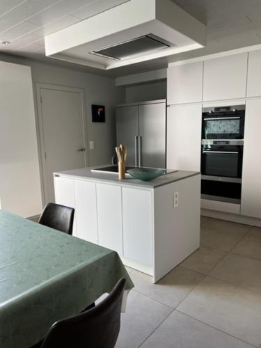 布鲁日MORI的厨房配有白色橱柜和桌椅