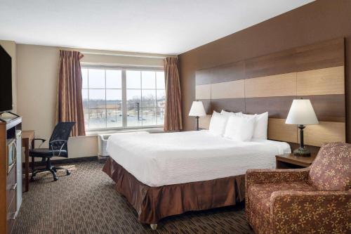 锡达拉皮兹AmericInn by Wyndham Cedar Rapids North的酒店客房带一张大床和一把椅子