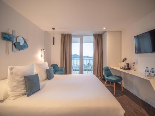滨海巴纽尔斯Côté Thalasso Hôtel & Spa Marin的酒店客房设有一张白色大床和一张书桌