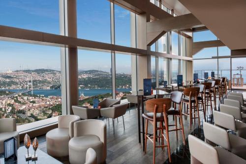 伊斯坦布尔文艺复兴时期伊斯坦布尔博斯普鲁斯波拉特酒店的餐厅设有桌椅和大窗户