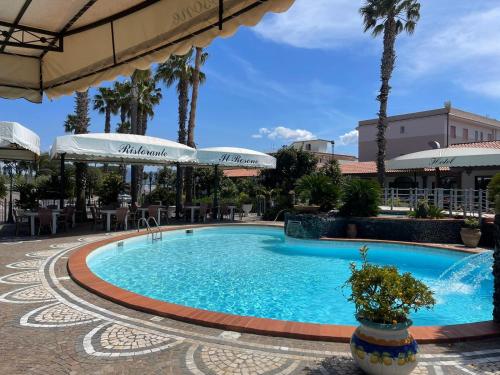 泰卡斯Hotel il Rosone的棕榈树度假村内的游泳池