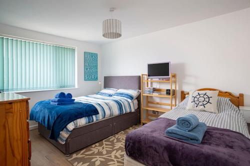 滨海比格伯里Fairwinds,Bigbury on sea ,Three-bed Beach House的一间卧室配有两张床和电视。