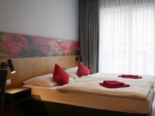 卢斯特瑙林德辛诺豪斯酒店的一间卧室配有一张带红色枕头的床和一扇窗户