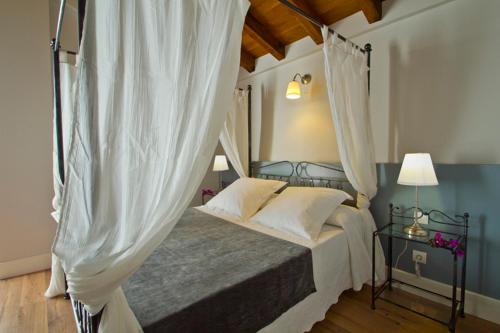 蓬特维耶斯戈阿尔塞酒店的卧室配有带白色窗帘的天蓬床
