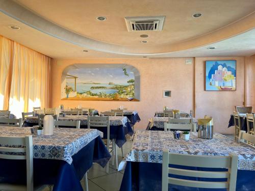 伊斯基亚罗塞塔酒店的餐厅配有桌椅和蓝白桌布