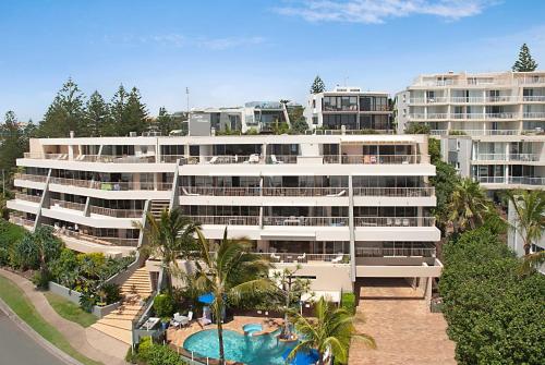 阳光海岸哥斯达新星假日公寓的一座白色的大建筑,前面设有一个游泳池
