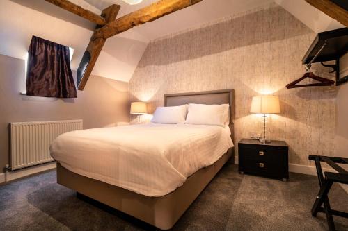 韦尔斯天鹅马房酒店的一间卧室配有一张大床和电视