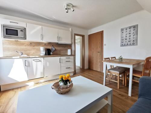 巴尔特鲁姆Ferienhaus Strandlust的厨房配有白色橱柜和鲜花桌