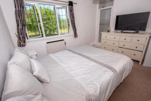 伍拉科姆Horizons的卧室配有白色的床和电视。