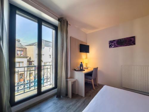 坎佩尔Hotel De La Gare的配有一张床、一张书桌和一扇窗户的酒店客房