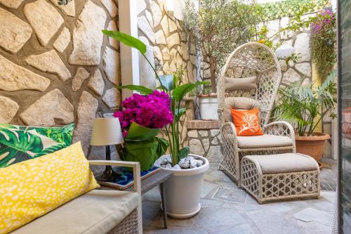 卡普里Suite Apartment Capri con Jacuzzi in Piazzetta的庭院设有藤椅和鲜花及植物