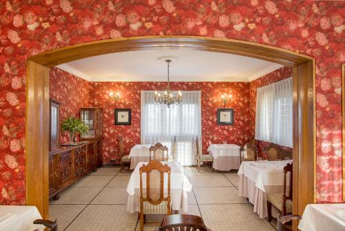 HontoriaHotel Hontoria的用餐室配有桌子和红色壁纸
