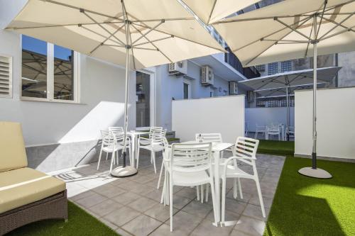 庞特维德拉Bulezen Urban Hostel的庭院配有白色的桌椅和遮阳伞。