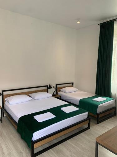 博尔若米Polifonia Inn Borjomi的绿窗帘间内的两张床