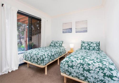凯阿玛Noorinan Getaway的一间卧室设有两张床和窗户。