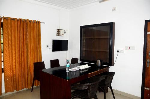 瓦亚纳德Misty Ghats Resort的配有桌椅和电视的客房