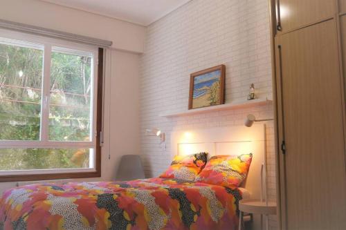 雷凯蒂奥AMANE Lekeitio, Parking Incluido的一间卧室配有一张带五颜六色的被子的床和窗户