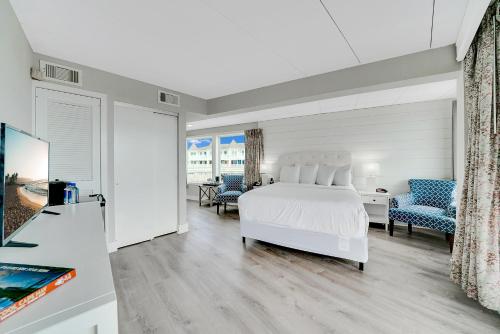 五月岬郡蒙特利尔海滩度假酒店的卧室配有白色的床和蓝色的椅子