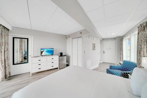 五月岬郡蒙特利尔海滩度假酒店的一间白色卧室,配有床和电视