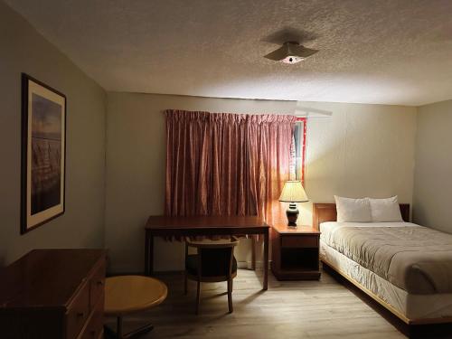 EstevanUptown Motel的配有一张床、一张书桌和一扇窗户的酒店客房