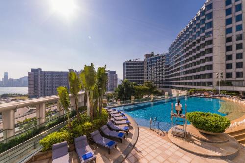 香港香港都会海逸酒店的游泳池位于带椅子的阳台和大楼内