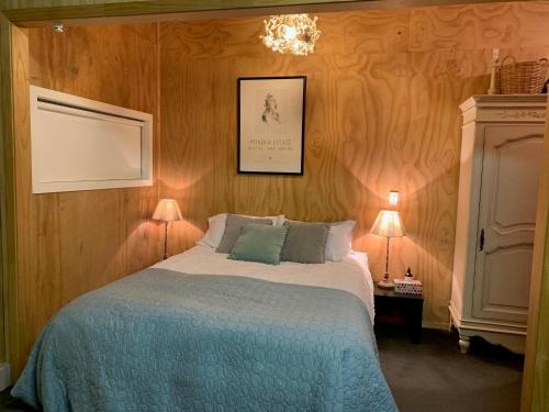 惠灵顿BENROSE FARM COTTAGES的一间卧室配有一张带蓝色毯子和两盏灯的床。