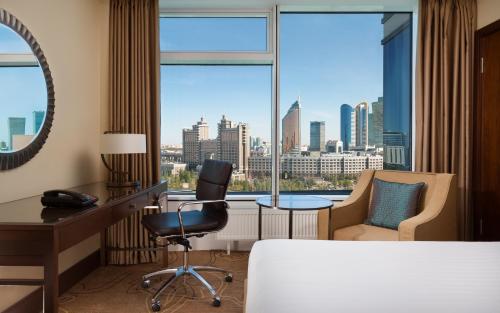 阿斯塔纳SAAD Hotel Astana的酒店客房设有一张桌子、椅子和窗户。