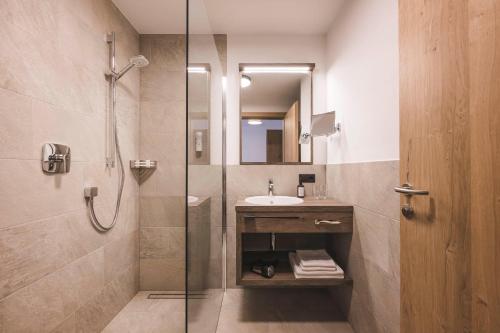 拉辛Hotel Schölzhorn Superior的一间带玻璃淋浴和水槽的浴室