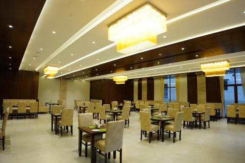 DharmastalaThe Ocean Pearl Dharmasthala Ujire的用餐室配有桌椅和吊灯。