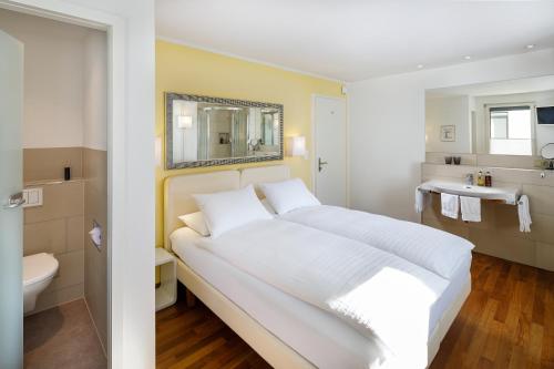 苏黎世施密特家庭酒店的一间带白色大床的卧室和一间浴室
