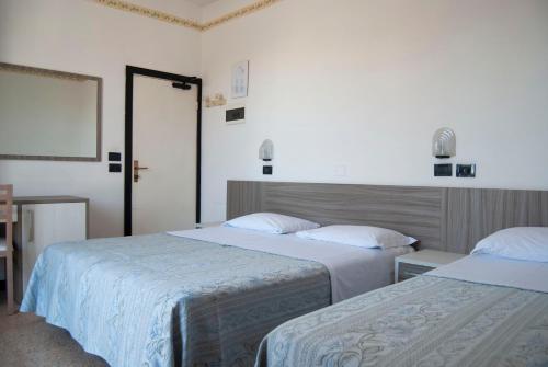 里米尼阿尔德西亚酒店的一间卧室配有两张带白色床单的床